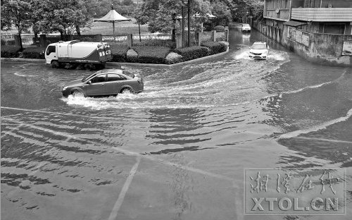  ６月１５日，一场暴雨致使城区许多道路积水，图为湘钢洪盛物流公司附近路段，车辆小心翼翼通过。（记者 陈旭东 摄）